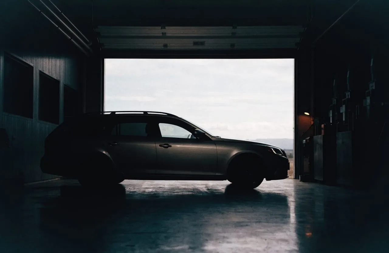 An estate car in the open roller-door bay of the workshop.